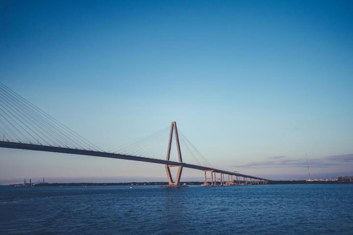 Cable-stayed bridge over a calm body of water under a clear blue sky.