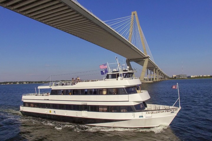 Boat cruising under a large cable-stayed bridge on a sunny day.