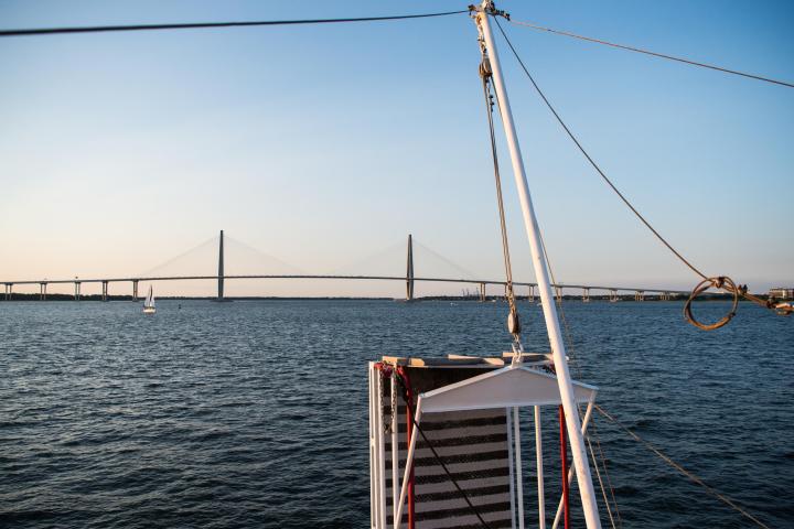 Sailboat view of a cable-stayed bridge over calm blue water.