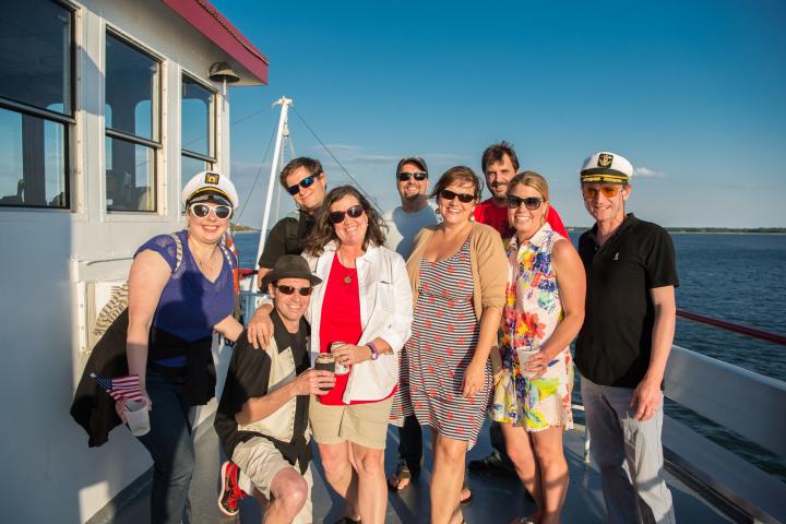 Group of people wearing sunglasses and casual clothes on a boat.