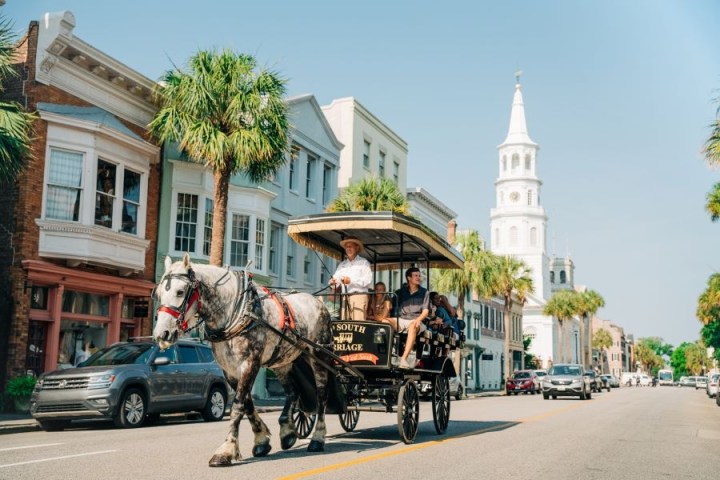 Horse-drawn carriage on a street with historic buildings and a church spire.