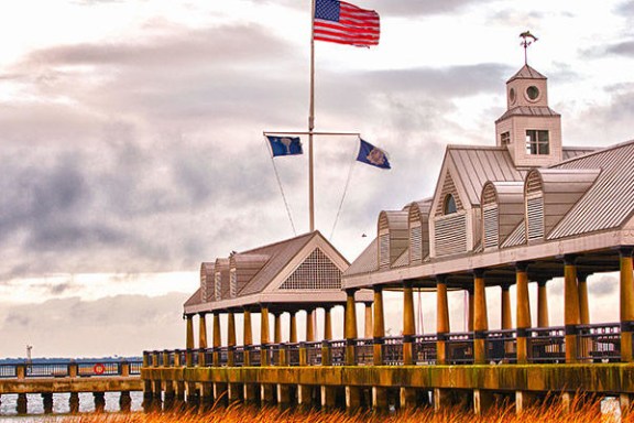Pier with American flag, gazebo structures, overcast sky.