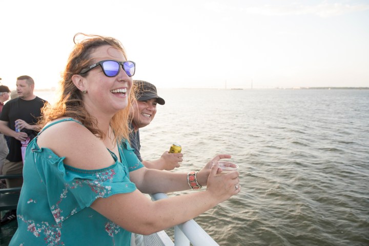 Two people smiling on a boat overlooking the water.