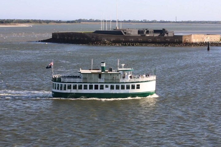 Boat on water passing near a fort on an island.