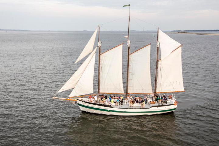 Three-masted sailing ship with passengers on open sea.
