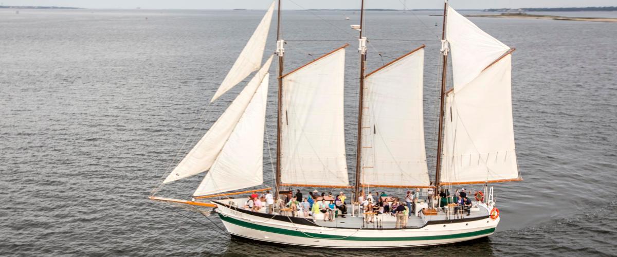 Three-masted sailing ship with passengers on open sea.