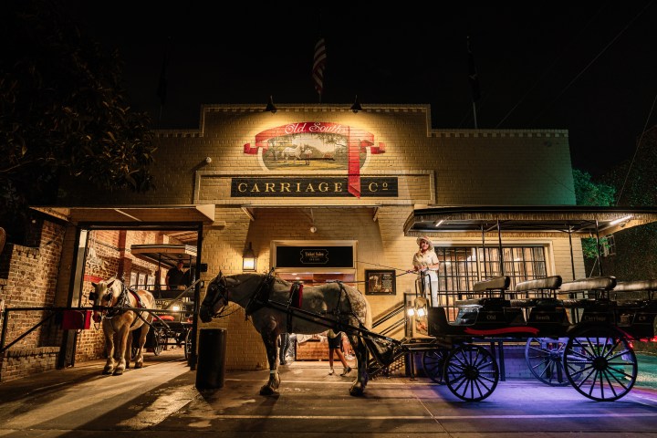 Horse-drawn carriage in front of a brick building at night.