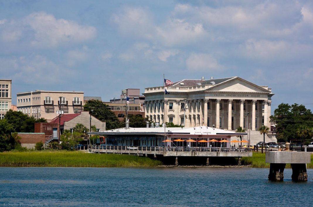 Historic building with columns by a waterfront under a blue sky.