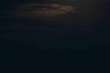 Full moon over a dark ocean with a reflection on the water.