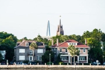 Historic houses with a church spire and bridge in the background.