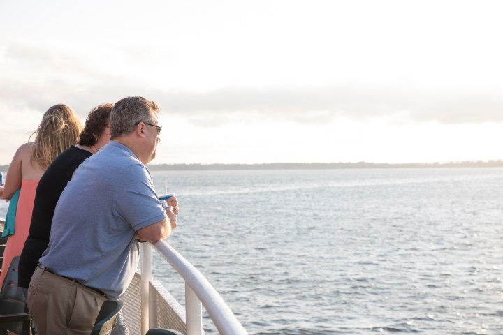 People on a boat looking out at the sea during sunset.