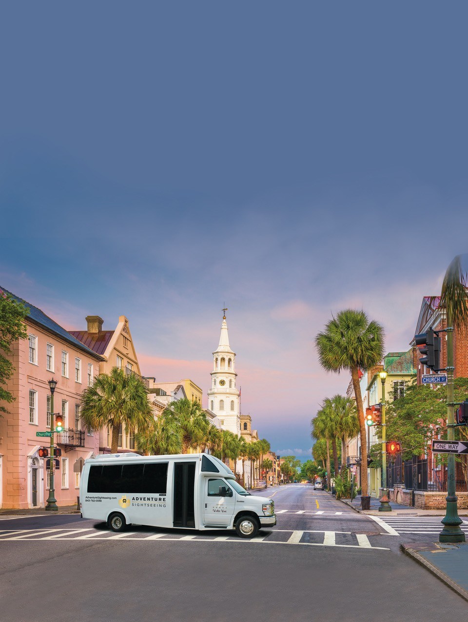 White van on empty street with historic buildings and church tower.
