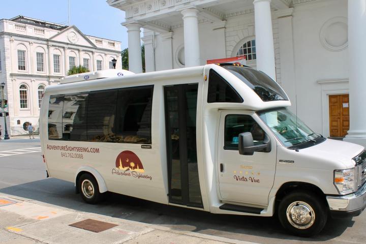 White tour shuttle parked on a city street corner.