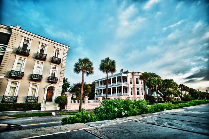 Historic buildings and palm trees under a blue sky with clouds.